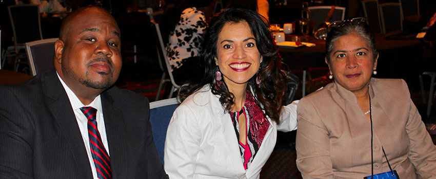 Dr. Andre Green with two other participants of the Conference sitting at a table.