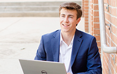 Male student working on his laptop outside