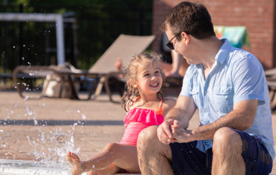 Dad with daughter splashing in pool