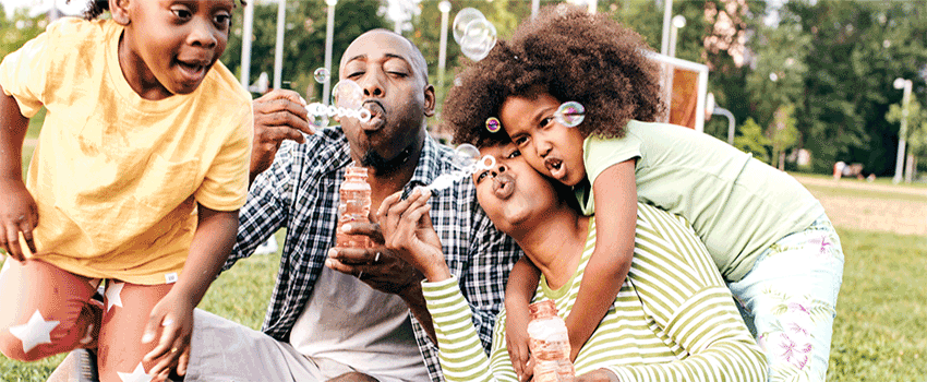 Family Playing with Bubbles outside on the grass.