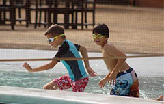 Two boys running in pool with goggles on.