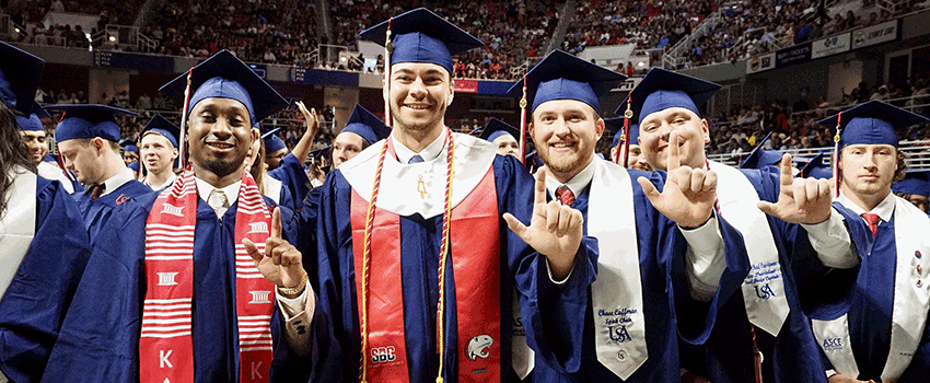 Graduate holding diploma and showing Jaguar sign